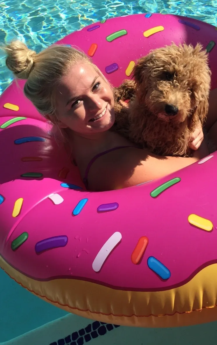 A woman and her dog are in an inflatable donut.